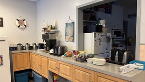 A kitchen with wooden cabinets, a coffee maker, toaster, and a fire extinguisher. - LEISURE INN (Temiskaming Shores)
