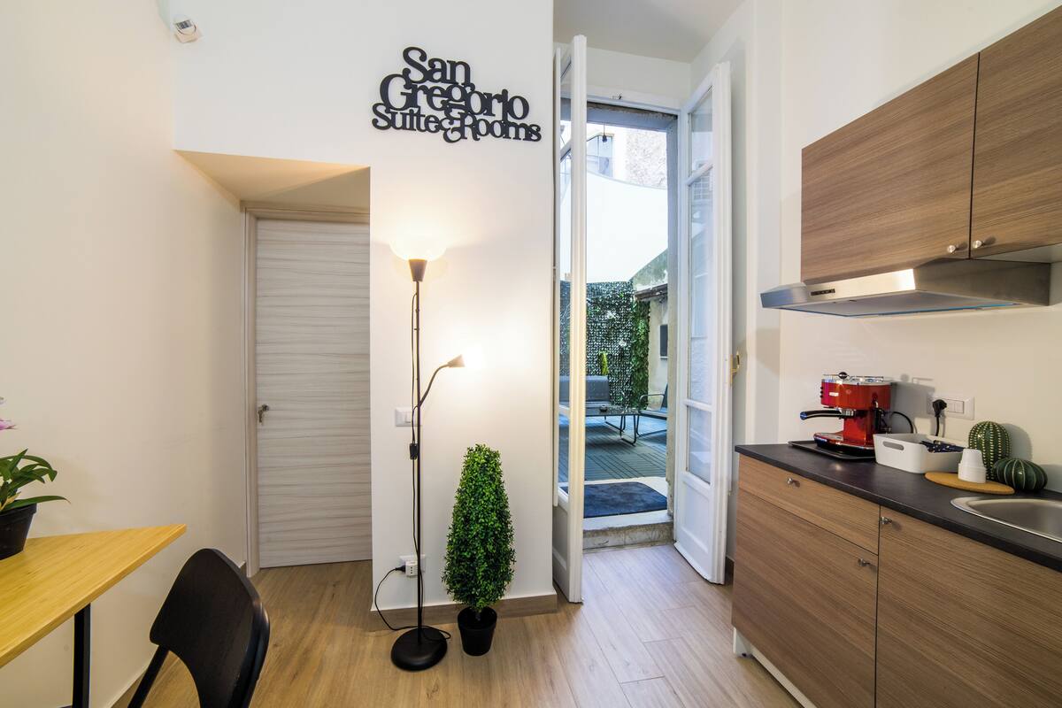 A compact kitchen with a coffee machine, a potted plant, and a small table.