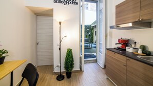 A compact kitchen with a coffee machine, a potted plant, and a small table.