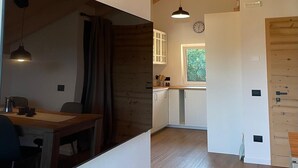 Een moderne keuken met houten balken, een eethoek met tafel en stoelen, en een raam dat voor daglicht zorgt.