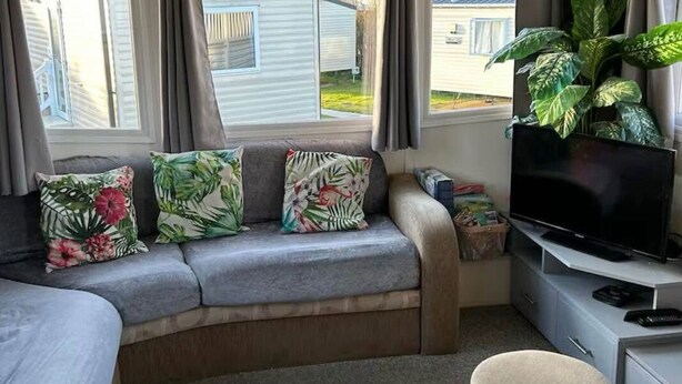 A cozy RV interior with a sofa, TV, and a dining area. - Popular resort- with indoor and outdoor pool (Newquay)