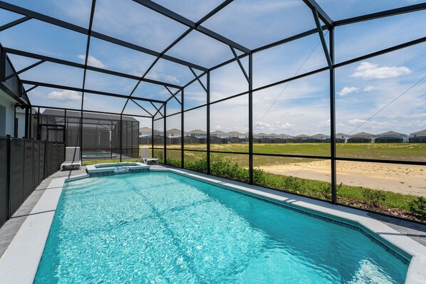 A swimming pool with a clear view of the surrounding landscape, enclosed by a metal frame structure.