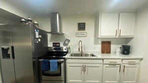 Een moderne keuken met roestvrijstalen apparatuur, witte kasten en een marmeren aanrecht.