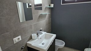 Et moderne badeværelse med en hvid vask, et spejl og et toilet.