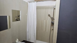 A bathroom with a sink, mirror, shower, and a towel rack.