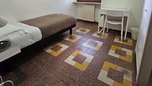 A small, clean room with a bed, a desk, and a radiator. - Single Room with Shared Bathroom and Private Parking in Loco (Potenza)