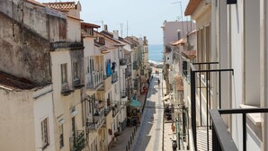 A narrow cobblestone street lined with buildings, some with balconies and others with ground-level shops. - Casa das Sardinhas - 2 minutes walk from the beach (Nazaré)