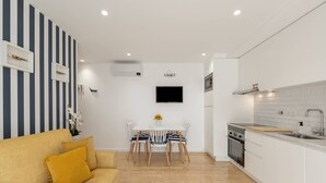 A compact living space with a sofa, dining table, and kitchen area. - Casa das Sardinhas - 2 minutes walk from the beach (Nazaré)