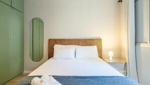 A neatly arranged bedroom with a bed, a nightstand, a green wardrobe, and a wall-mounted mirror. - Apto Central a 600m da Beira-Mar Norte SGS0106 (Florianópolis)