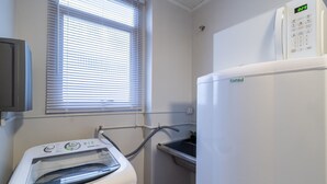 A laundry area with a washing machine, a dryer, and a microwave. - Apto Central a 600m da Beira-Mar Norte SGS0106 (Florian ópolis)
