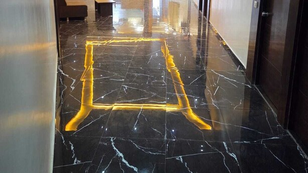 A hotel corridor with a polished marble floor, a reception desk, and a seating area. - HOTEL SAROVAR GRAND  (Ahmedabad)