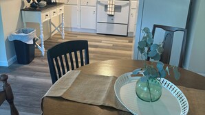 A compact kitchen with white cabinets, a microwave, an oven, and a refrigerator. - Charming 2-bedroom barn-style home nestled on 6 acres in delightful Vienna (Vienna)