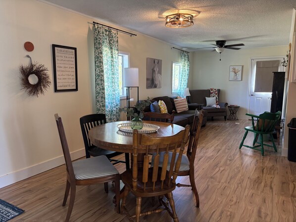 A dining area with a round wooden table, chairs, and a chandelier.