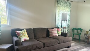 A brown sectional sofa with floral cushions, a green chair, and a small table with a potted plant. - Charming 2-bedroom barn-style home nestled on 6 acres in delightful Vienna (Vienna)