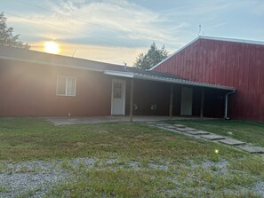A single-story house with a red barn, a covered porch, and a gravel driveway.