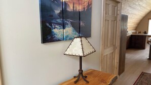 Una mesa de madera con una lámpara y un tríptico colgado en la pared.