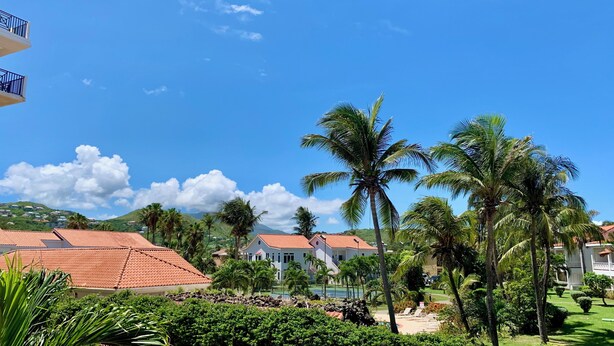 Un resort con piscina, palmeras y casas de techo rojo.