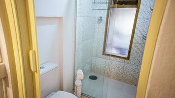 A small bathroom with a toilet, a glass shower enclosure, and a tiled floor.
