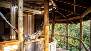 A wooden structure with a hammock, a sign reading "Flor de Laranjeira," and a view of greenery outside. - Espaço Flor das Águas  (Cunha)