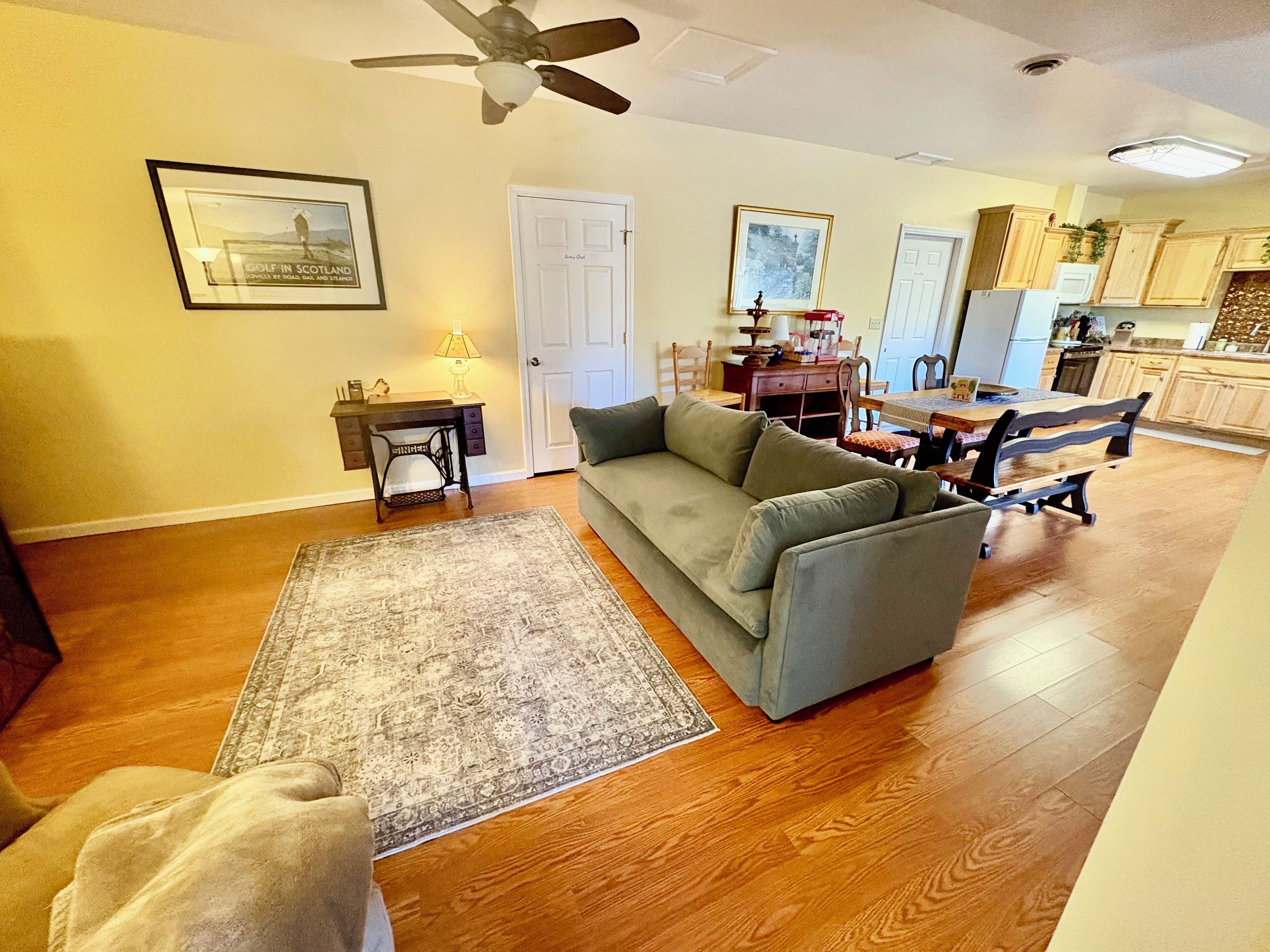 A living room with a sofa, a coffee table, a rug, and a ceiling fan.