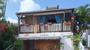 Een gebouw met twee verdiepingen, een balkon, bloempotten en een bordje met de tekst 'La Piramita'.