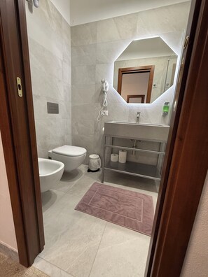 Ein modernes Badezimmer mit Toilette, Bidet und Waschtisch mit Spiegel.
