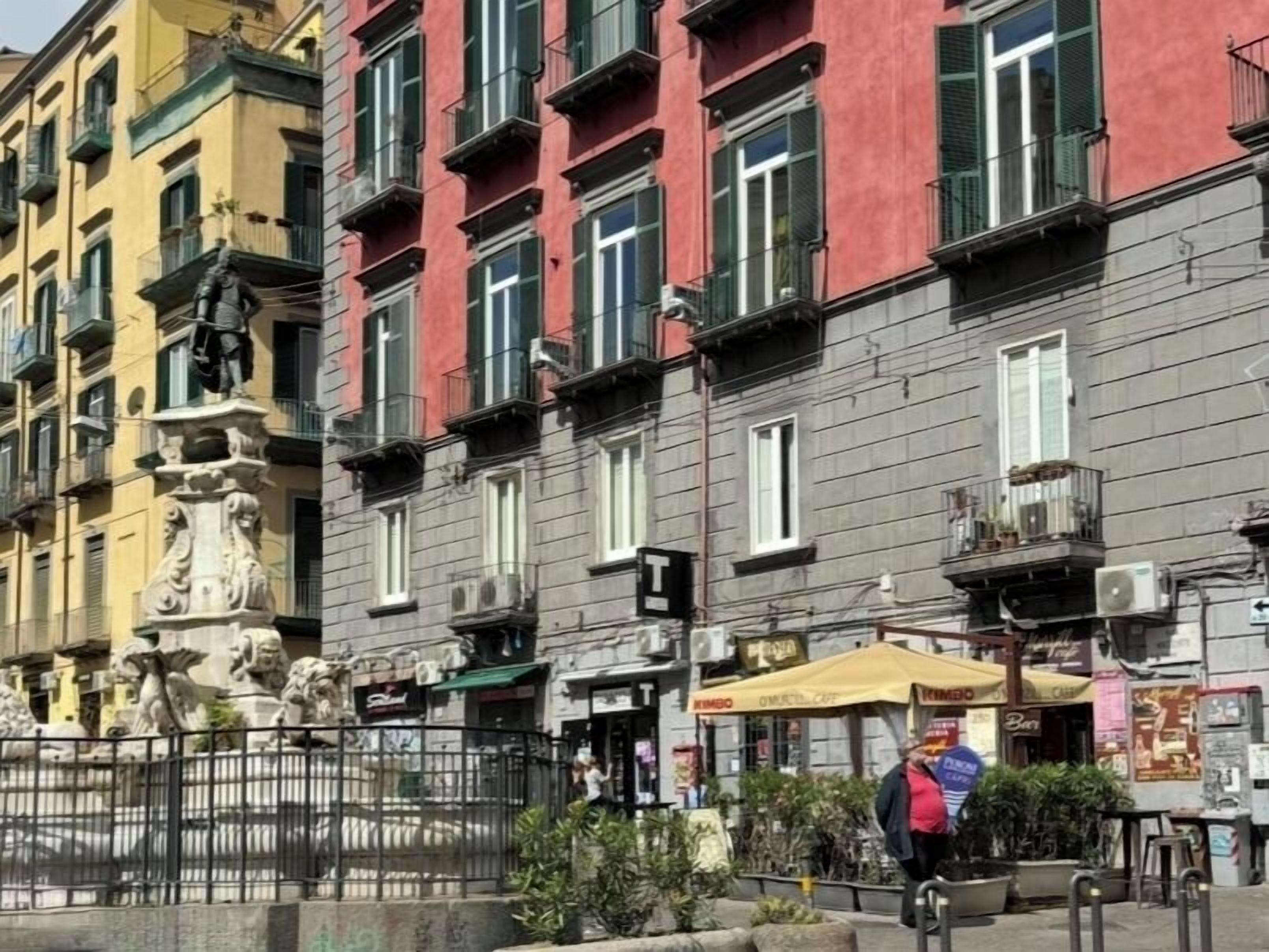 Une rangée de bâtiments colorés dotés de balcons, une statue et des espaces de détente en plein air.