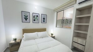 A bedroom with a bed, bedside tables, a nightstand, a window, and wall-mounted artwork. - Mar Serena Beachside Stay  (Cartagena)