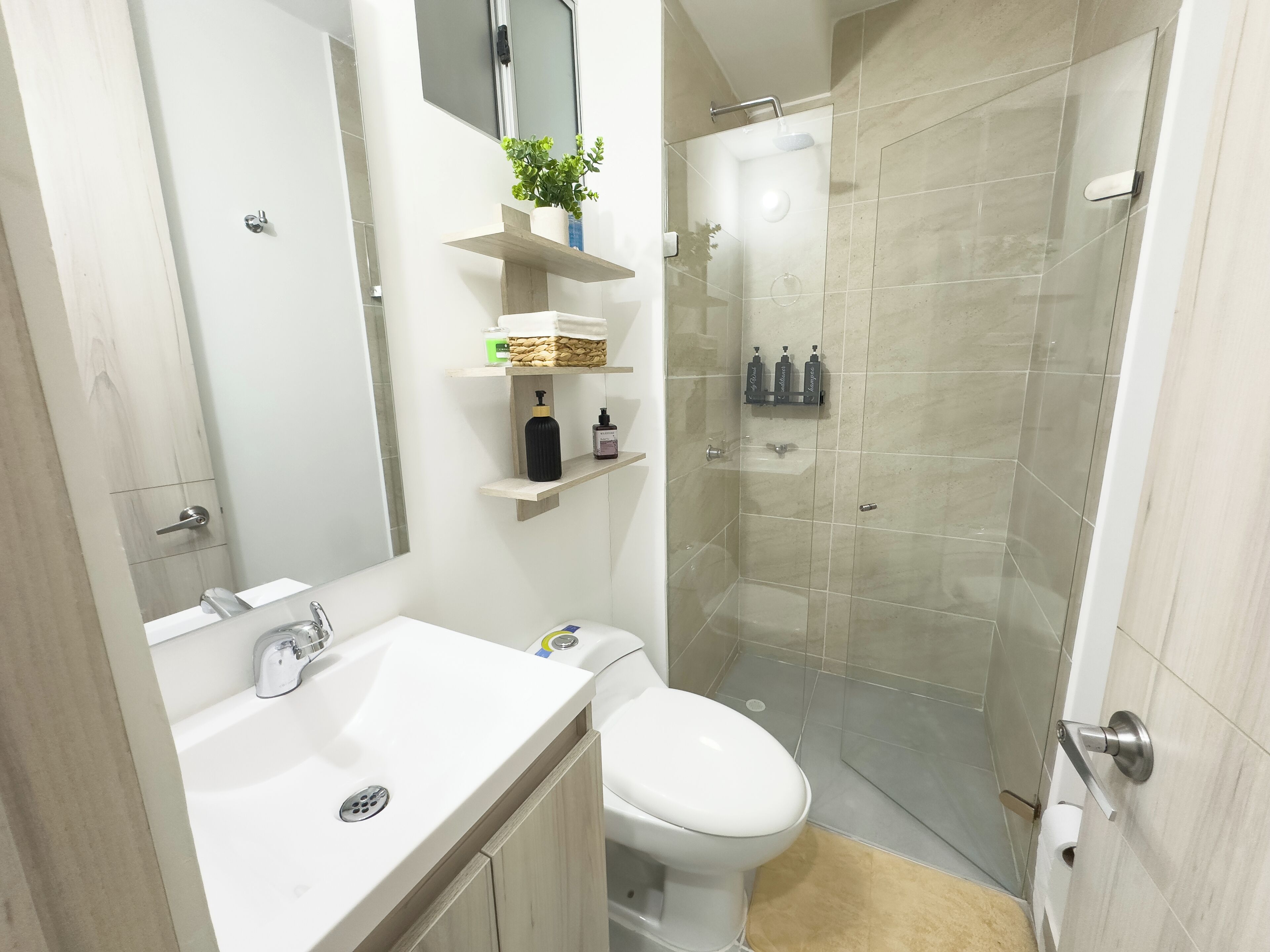 A modern bathroom with a white sink, toilet, and glass-enclosed shower.