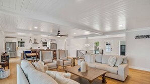 A spacious living area with a large sofa, a coffee table, and a dining area with chairs and a table. - Waterfront Elegance: Spacious 5BR Lake Home with Game Room & Private Dock Access (Osage Beach)