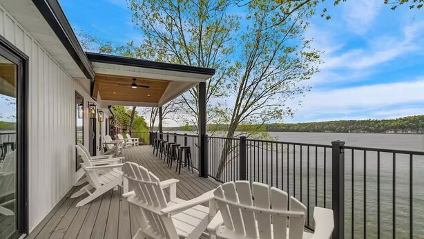 A wooden deck with white Adirondack chairs overlooking a body of water. - Waterfront Elegance: Spacious 5BR Lake Home with Game Room & Private Dock Access (Osage Beach)