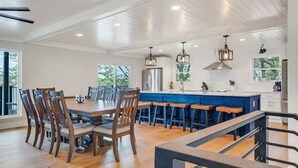 A spacious kitchen with a large island, wooden chairs, and pendant lighting. - Waterfront Elegance: Spacious 5BR Lake Home with Game Room & Private Dock Access (Osage Beach)