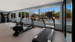 Ein modernes Fitnessstudio mit Cardiogeräten, großen Fenstern und Blick auf den Parkplatz.