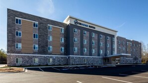 Ein modernes Hotelgebäude mit einer Natursteinfassade, mehreren Etagen und dem Schriftzug "Everhome Suites".