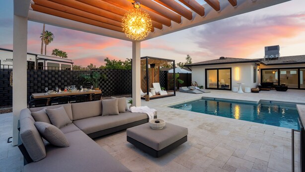 A modern outdoor living area with a pool, a covered seating area, and a dining setup.