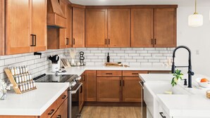 A modern kitchen with wooden cabinets, a white countertop, a stove, and a sink.
