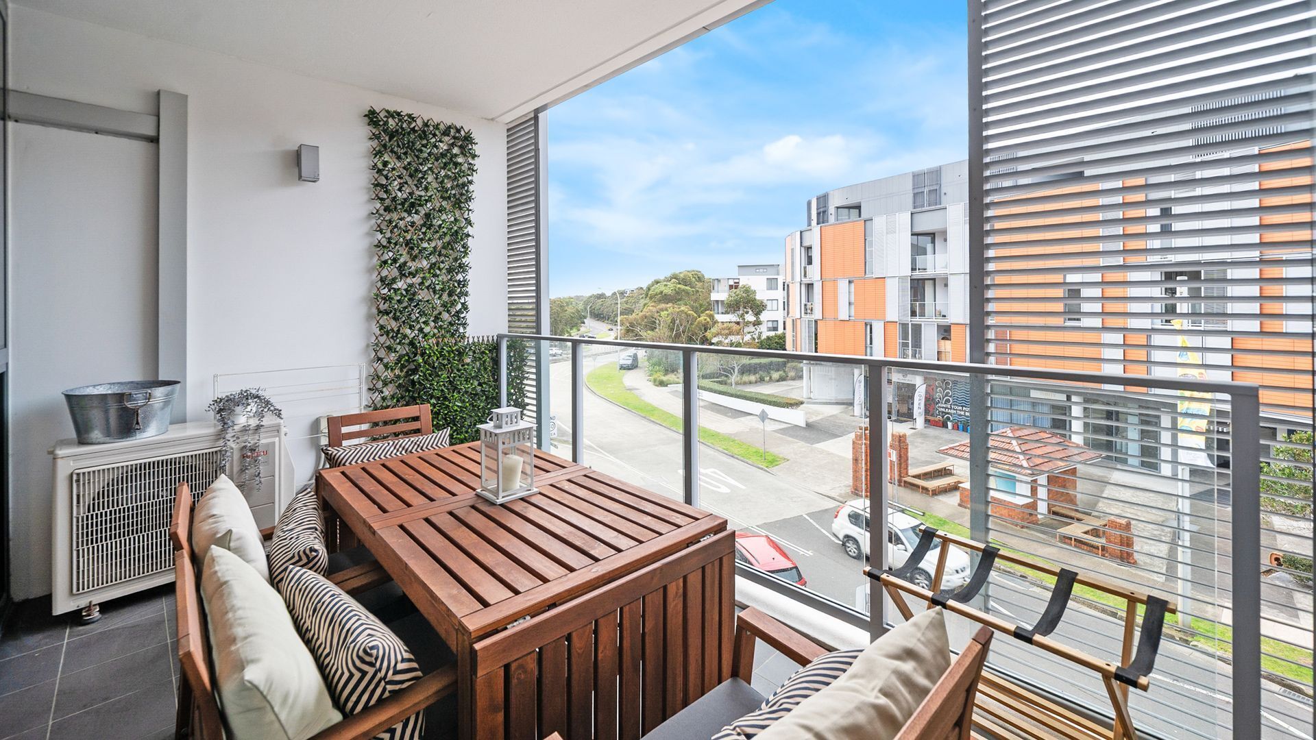 Ein Balkon mit Holztisch und -stühlen, einem Heizkörper und einer grünen Wand.
