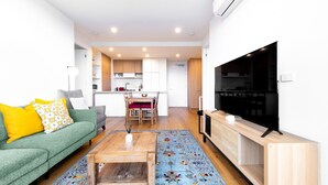Una sala de estar moderna con un sofá verde, una mesa de centro de madera y un televisor de pantalla plana.