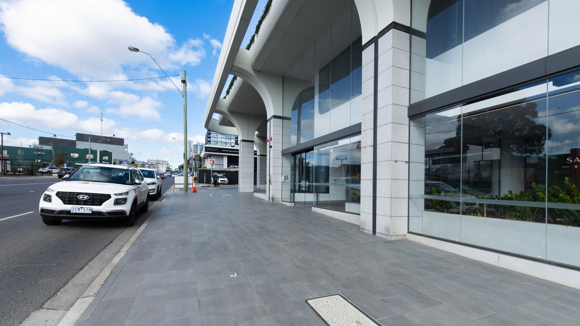 A modern building with large glass windows and a clean, paved sidewalk.