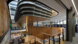 Un interior de biblioteca moderno con paneles de madera, un entrepiso y una variedad de estanterías.
