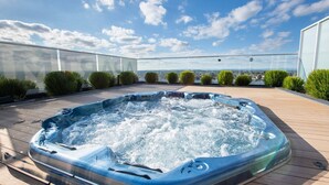 Un jacuzzi en una terraza de madera con una vista despejada del cielo y un paisaje lejano.