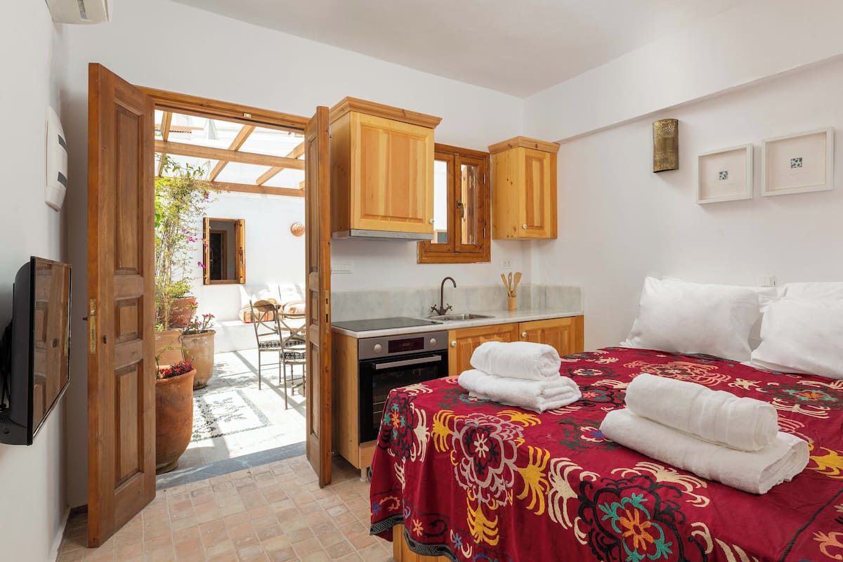 A compact hotel room with a bed, a small kitchenette, and a bathroom.
