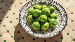 A decorative bowl with a patterned design containing several green limes. - Villa Vasoula Lindos  (Lindos)