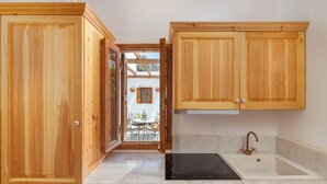 A kitchen with wooden cabinets, a dishwasher, an oven, and a sink. - Villa Vasoula Lindos  (Lindos)