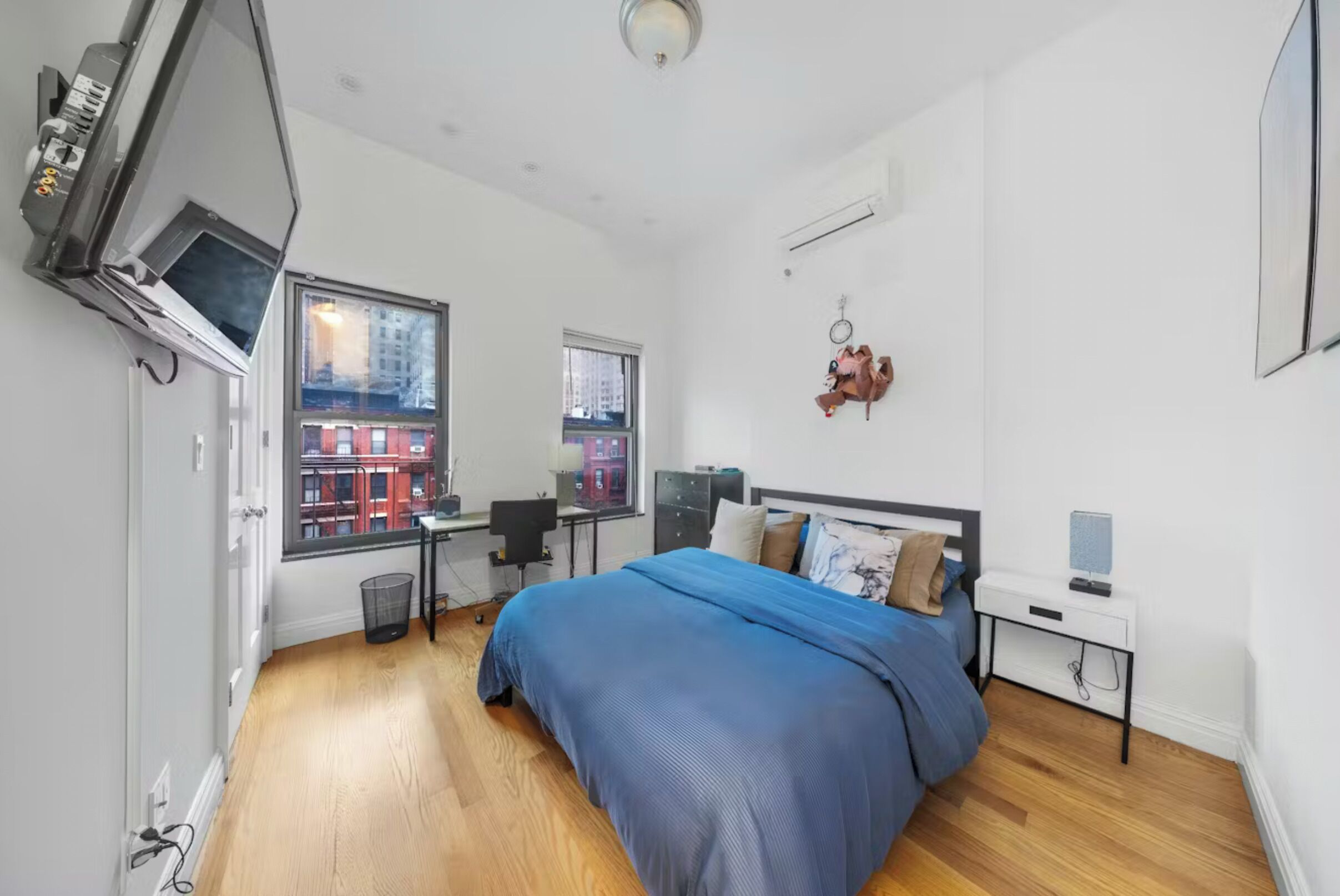 A modern bedroom with a large bed, a desk, and a TV.