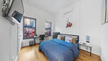 A modern bedroom with a large bed, a desk, and a TV.