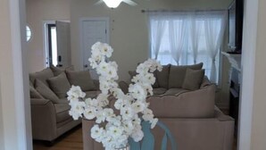A dining area with a round table, a vase with white flowers, and a ceiling fan.