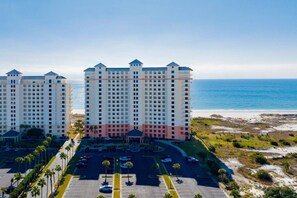 Un hôtel de grande hauteur, avec de nombreux étages, un parking et une vue sur la plage.