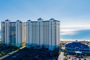 A high-rise hotel with multiple floors, a parking lot, and a beach view. - 19th Floor Oceanfront View at The Beach Club (Gulf Shores)
