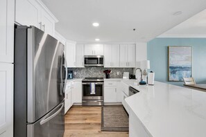 Una cocina moderna con armarios blancos, electrodomésticos de acero inoxidable y un elegante revestimiento en patrón de espiga.